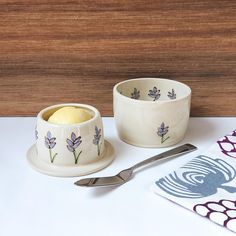 two bowls with spoons on a table next to a napkin and utensil