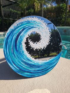 a blue and white glass sculpture sitting next to a swimming pool