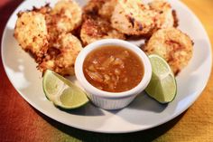 a white plate topped with food next to a bowl of sauce and two lime wedges