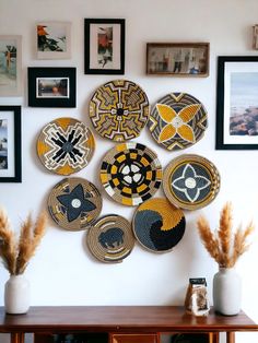 a bunch of plates are hanging on the wall above a table with some plants in front of it