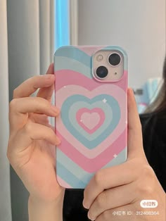 a woman holding up a phone case with a heart on it