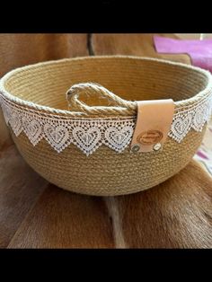 a woven basket with white lace on the bottom and a leather tag attached to it