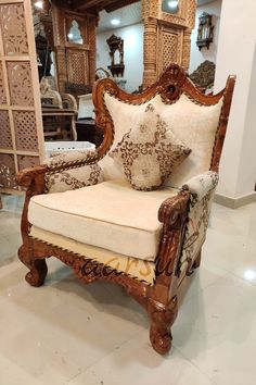 an ornate wooden chair with pillows on it in a room filled with furniture and mirrors