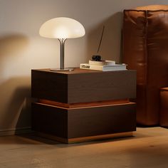 a lamp sitting on top of a wooden table next to a brown leather couch in a living room