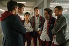 a group of young men standing next to each other in an office building, talking