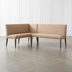 a beige couch sitting on top of a hard wood floor next to a white wall