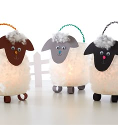 three sheep made out of fake wool with lights on their heads and ears, standing in front of a white fence