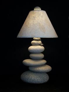 a lamp that is sitting on top of some rocks and has a white shade over it