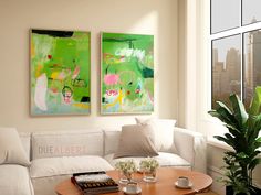 a living room with two paintings on the wall and a coffee table in front of it