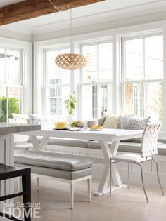 a dining room table with benches and chairs in front of large windows that look out onto the backyard