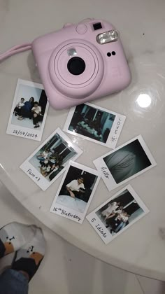 a pink camera sitting on top of a white table next to some polaroid pictures