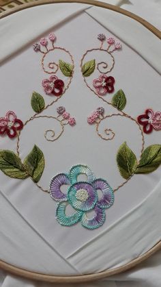 a white plate topped with a flower and leaves embroidered on it's side next to a basket