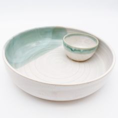 two bowls sitting on top of each other in front of a white background with blue swirls