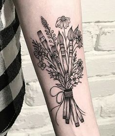 a woman's arm with flowers and paintbrushes tattoo on the left forearm