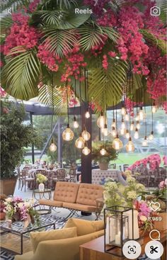 a living room filled with lots of furniture and flowers hanging from the ceiling above it