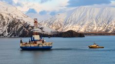 a large boat floating on top of a body of water near snow covered mountain range