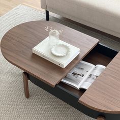 a coffee table with an open drawer underneath it and a magazine on the bottom shelf