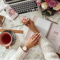 a woman's hand on her wrist next to a laptop computer and coffee cup