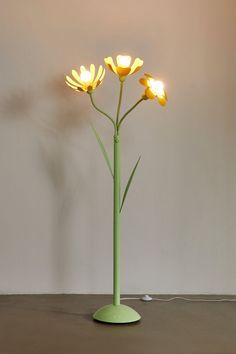 a green vase with three yellow flowers in it