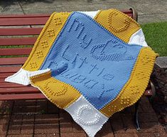 a crocheted blanket sitting on top of a wooden bench next to a park bench