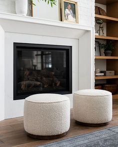 two white stools sitting in front of a fireplace