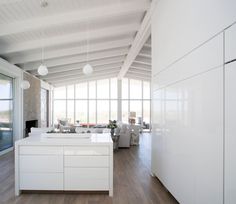 a large kitchen with white cabinets and counter tops next to a wall that has lots of windows