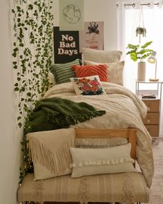 a bed with pillows and blankets on top of it next to a plant covered wall