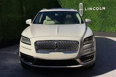 a white car parked in front of a lincoln sign