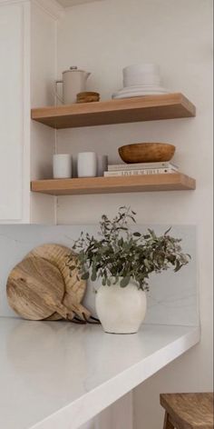 a kitchen counter with some wooden cutting boards and bowls on top of it, next to a potted plant