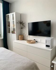 a flat screen tv sitting on top of a white dresser