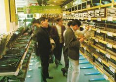 people looking at electronics in a store with shelves full of electronic equipment and other items