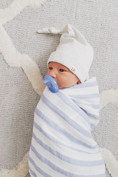 a baby wrapped in a blue and white blanket with a pacifier in it's mouth