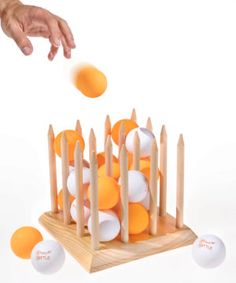 an orange and white ping pong game being played by a person's hand