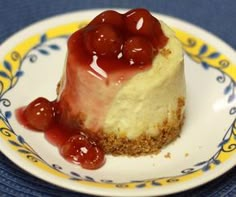 a piece of cheesecake with cherries on top sits on a blue and yellow plate