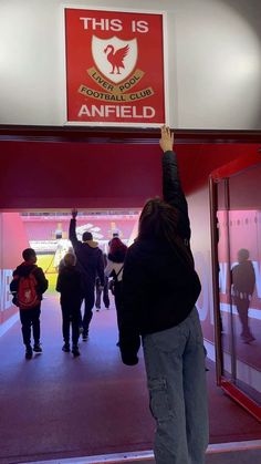 a person reaching up into the air in front of a sign that reads, this is anfield