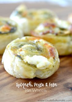 small pizzas with spinach, pesto and feta on top are sitting on a cutting board