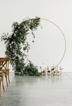 a table with chairs and flowers on it in front of a circular wall hanging from the ceiling