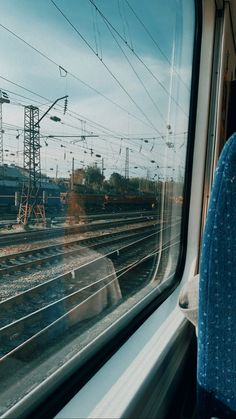 the view from inside a passenger train looking at tracks and power lines in the distance