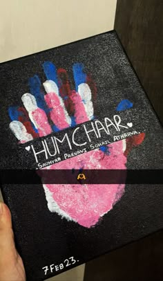 a person holding up a book with the cover painted pink and blue in front of them