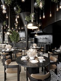 a restaurant with tables, chairs and chandeliers hanging from the ceiling