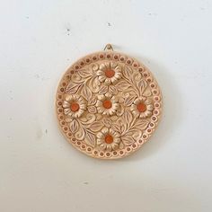 a wooden wall hanging with flowers and leaves on it's side, in the shape of a circle