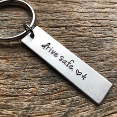 a metal keychain with the words alive safe on it sitting on a wooden surface