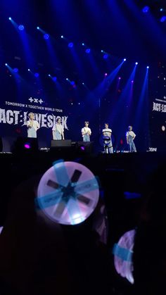 a group of people standing on top of a stage in front of a crowd at a concert