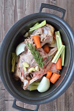 a pot filled with meat, carrots and celery on top of a wooden table