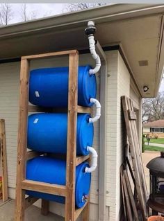 a ladder is holding three large blue barrels