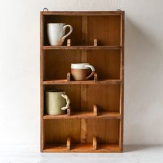 a wooden shelf with cups and mugs on it