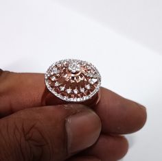 a close up of a person's hand holding a ring with diamonds on it