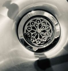 a close up of a metal sink with a circular design on the drain and water running through it