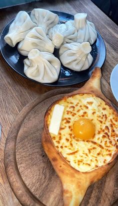 some food is sitting on top of a wooden table next to other plates and utensils