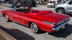 an old red convertible car parked on the street